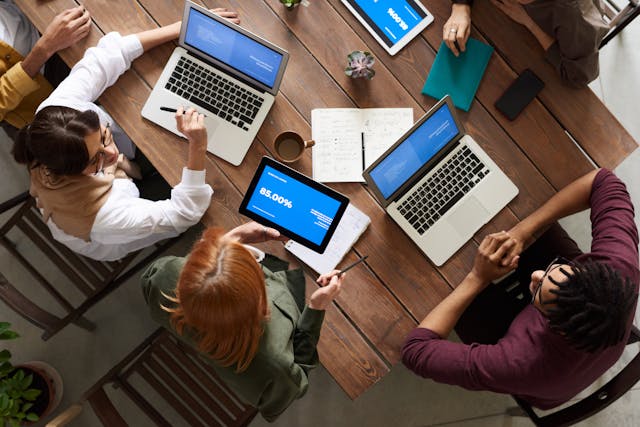 A team of software developers collaborating on a software product engineering project while working on laptops and digital devices.