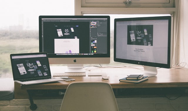 A workspace with multiple devices, including a laptop, desktop computer, and smartphone, all open to collaboration software.